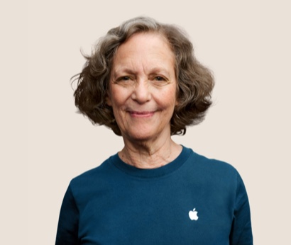 Portrait of a smiling Apple Retail team member with wavy, dark gray hair.