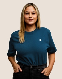 Portrait of a smiling Apple Retail team member with long, dark blond hair.