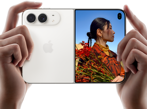 iPhone Duo, Star White color, held by two hands in horizontal orientation, unfolded, left panel shows 48MP Dual Fusion rear cameras, right panel shows person getting their picture taken on outer display, the subject of the photo is able to see their face as their picture is getting taken using Duo Preview
