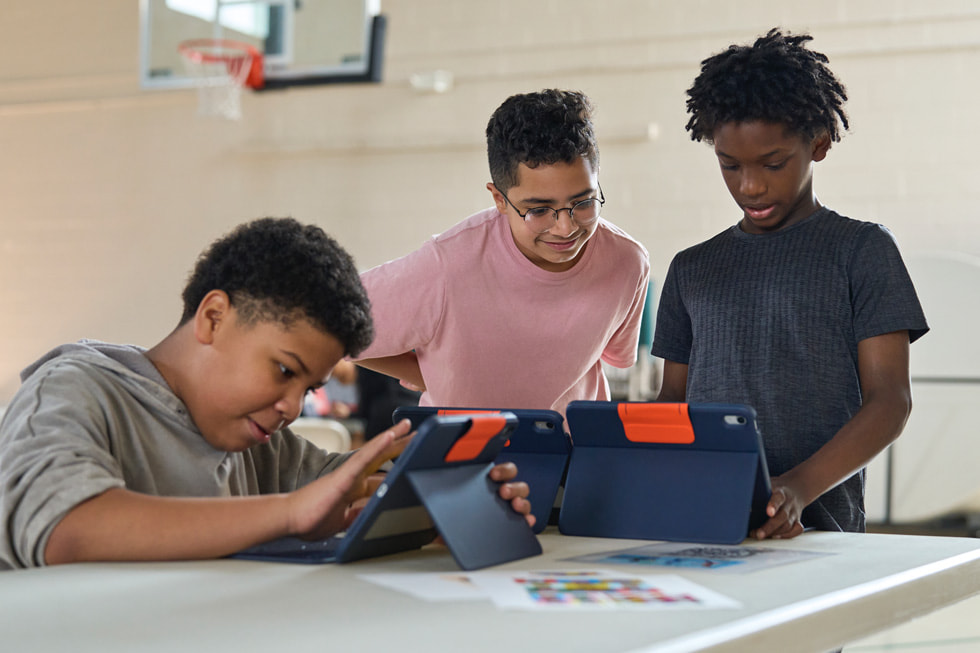 Un instructor de 4-H trabaja con jóvenes estudiantes usando un iPad durante el campamento de STEM Explorers.