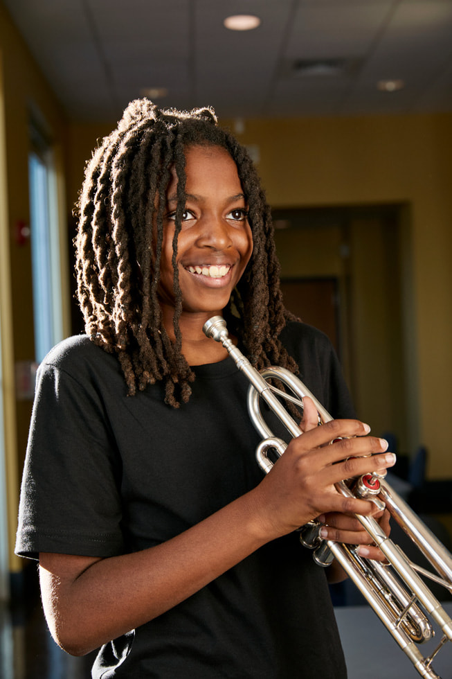 Ellis Marsalis Center participant Donte Allen plays the trumpet outside of the centre.