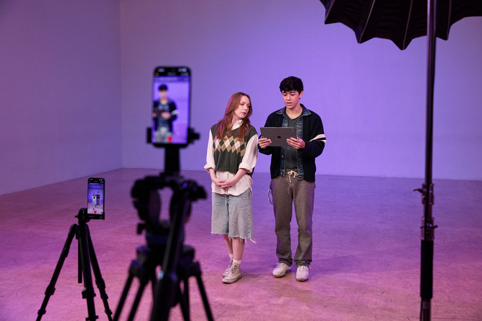 Zwei iPhone 17 Pro Max auf Stativen nehmen Kyle Hanagami und eine:n Tänzer:in in einem Studio auf. 
Hanagami hält ein iPad Pro.