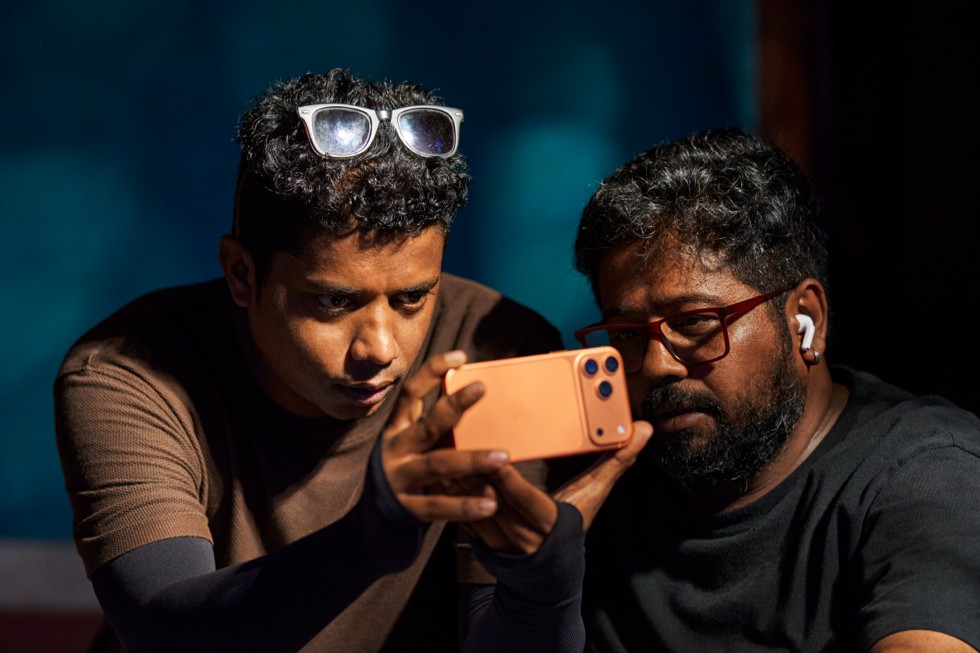 Robin Joy e um colega observam atentamente um iPhone 17 Pro Max.
