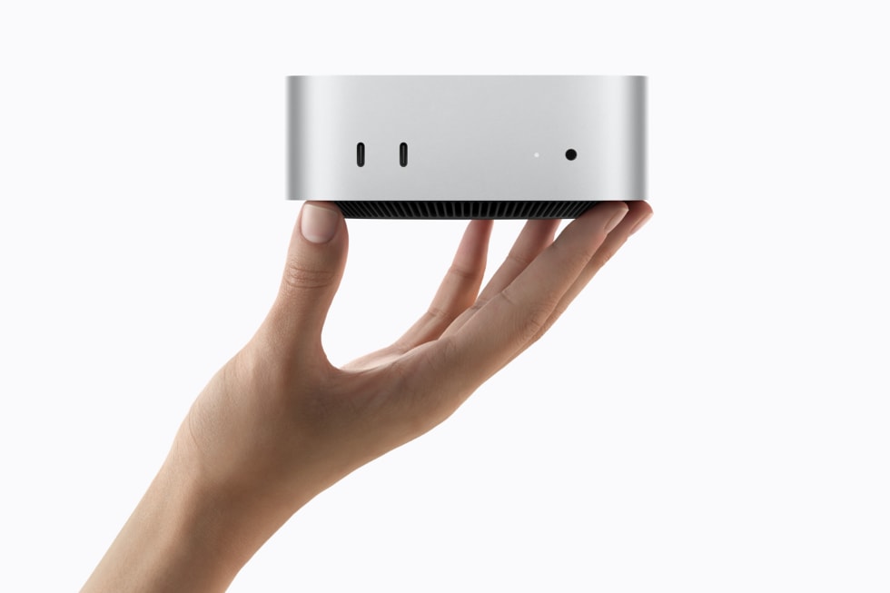 En hånd holder Mac mini op mod en hvid baggrund.