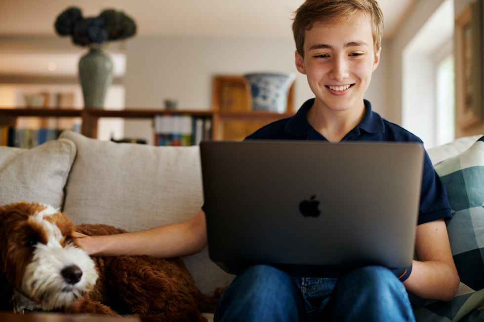 Der junge App Entwickler Ben arbeitet zu Hause an seinem MacBook Pro.
