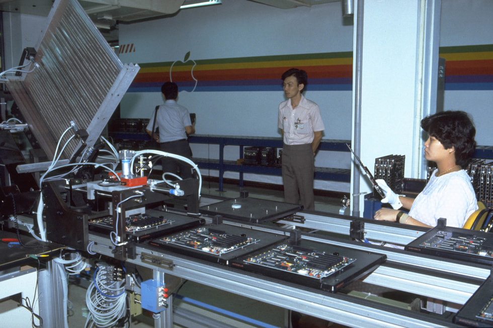 Facility workers in front of an assembly line for Apple IIe.