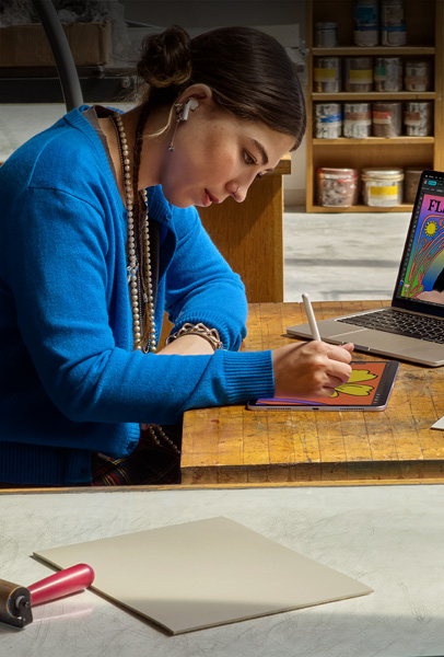 Una estudiante sentada en un escritorio dibuja en un iPad con un Apple Pencil