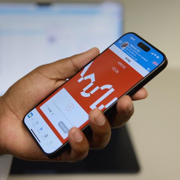 A hand holding an iPhone displaying the Abridge app that translates patient–clinician conversations into clinical notes.