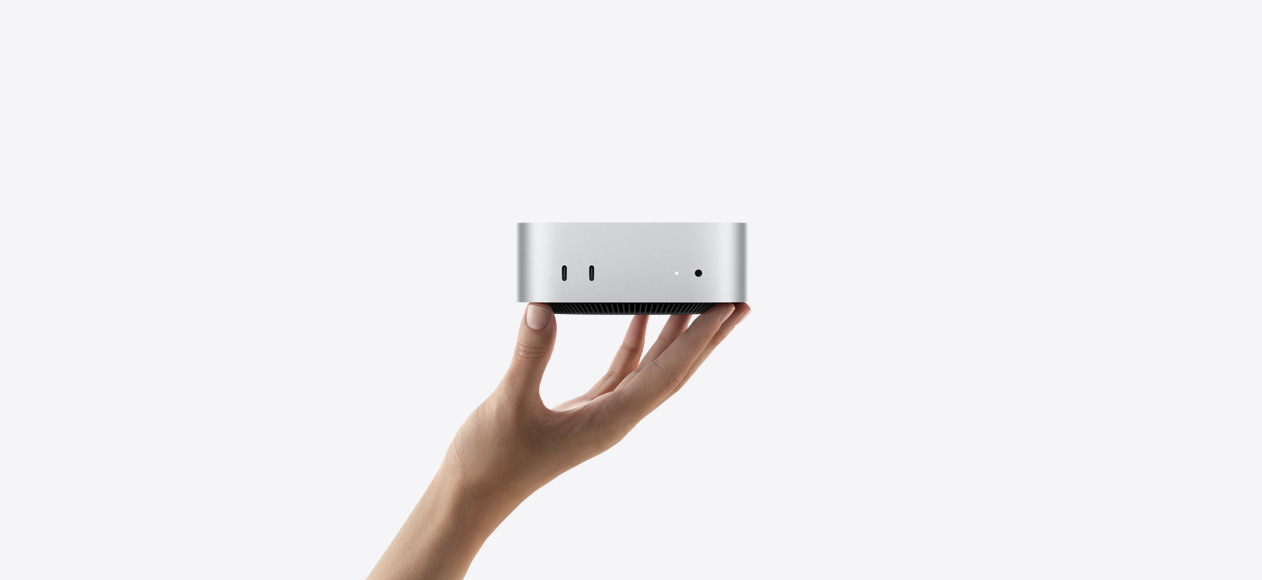 Mac mini esikülg üles sirutatud käe sõrmeotstel tasakaalus, esiküljel on kaks Thunderbolt-liidest, olekutuli ja kõrvaklapipesa, all kitsenev must alus, lame ülaosa, ümarad küljed, sirged servad, hõbedane värvitoon