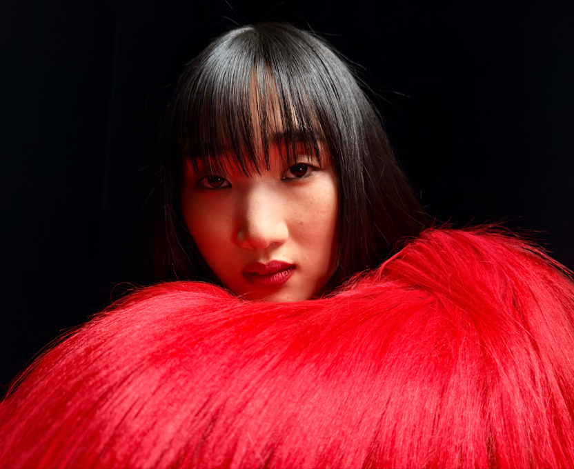 Gros plan d’une femme vêtue d’un haut à plumes rouge vif illustrant les capacités photographiques super haute résolution de l’iPhone 17 Pro