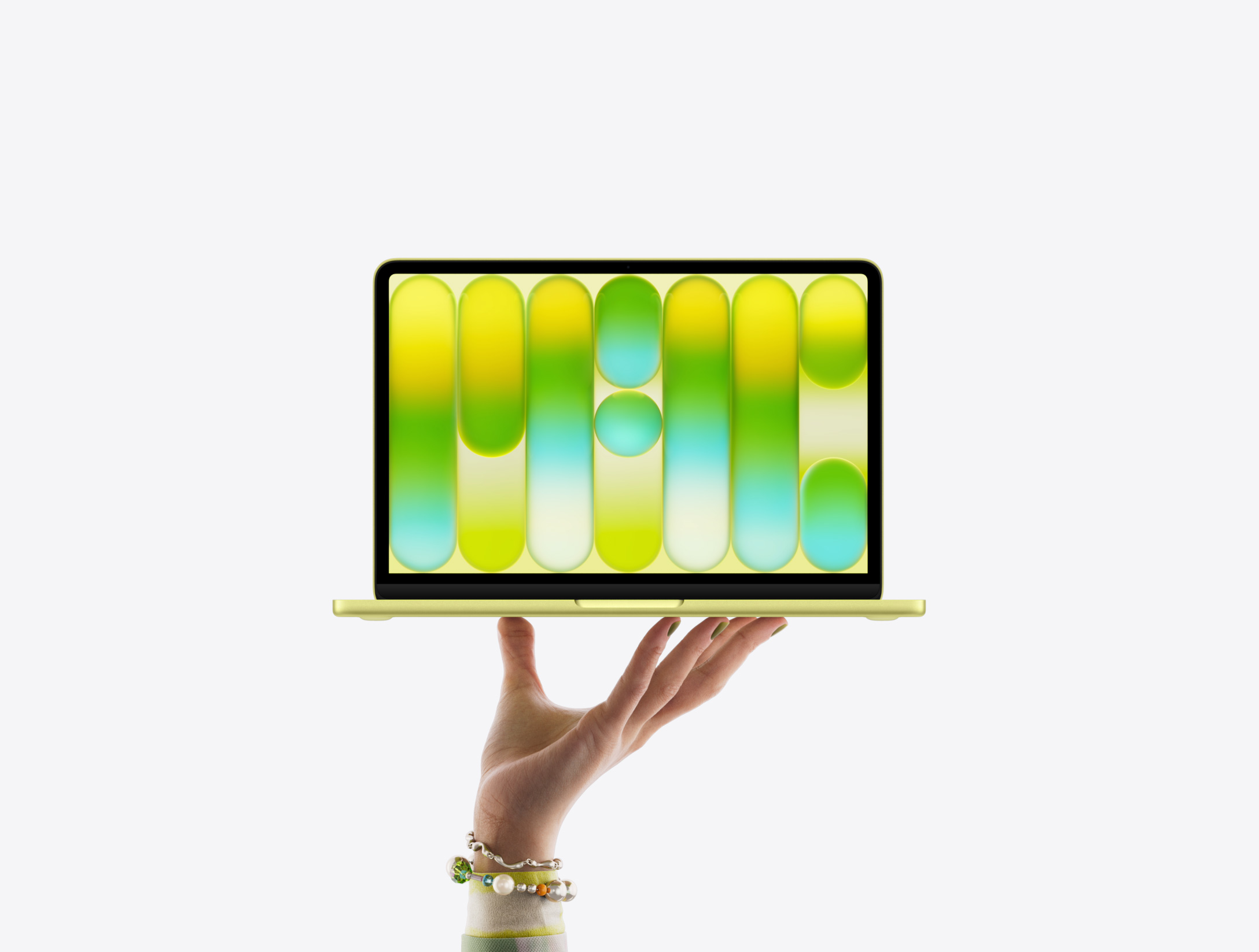 MacBook Neo couleur jaune agrume, en équilibre sur le bout des doigts d’une main ouverte, écran affichant un motif abstrait coloré