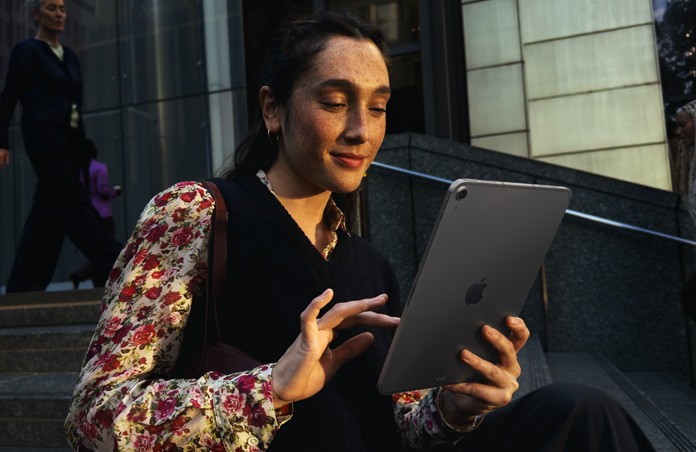 Una persona seduta sui gradini di un ampio palazzo che usa un iPad Air 11 pollici grigio siderale, con connessione Wi‑Fi stabile per trasferire dati in rete