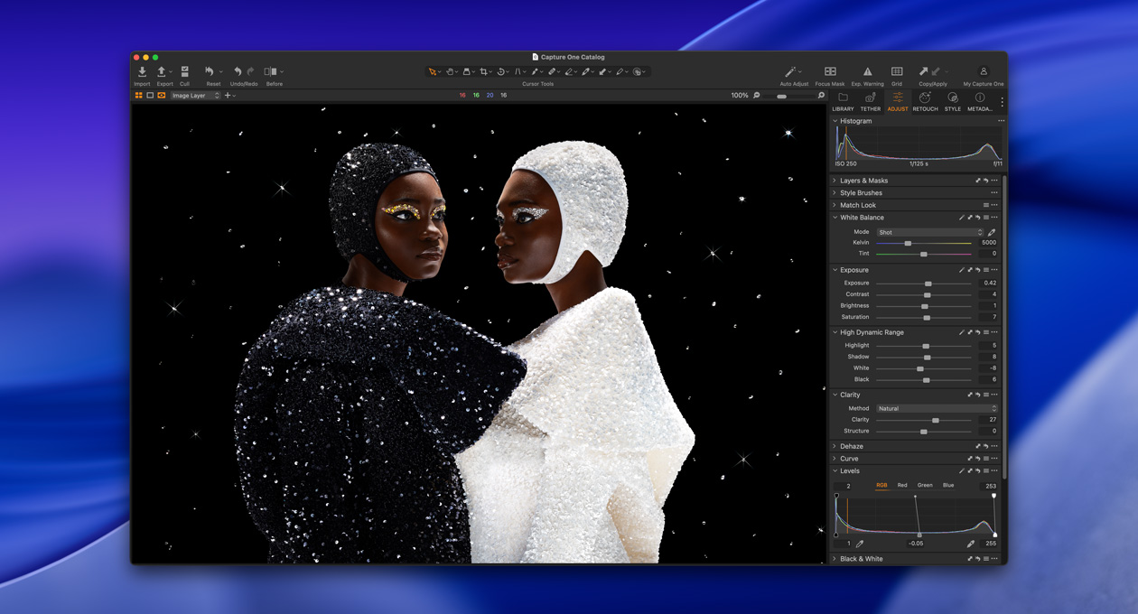 A person wearing black stands angled next to a person in white, showcasing the brightness and contrast available with Studio Display XDR