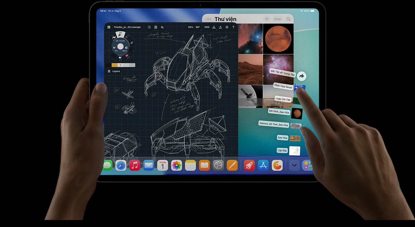 iPad Pro, front exterior, landscape orientation, right hand gesturing over Downloads folder files fanned out, display showing iPadOS 26 interface with multiple open apps including photo editing app with detailed robot blueprints and handwritten annotations and multiple design stages, and Photos Library